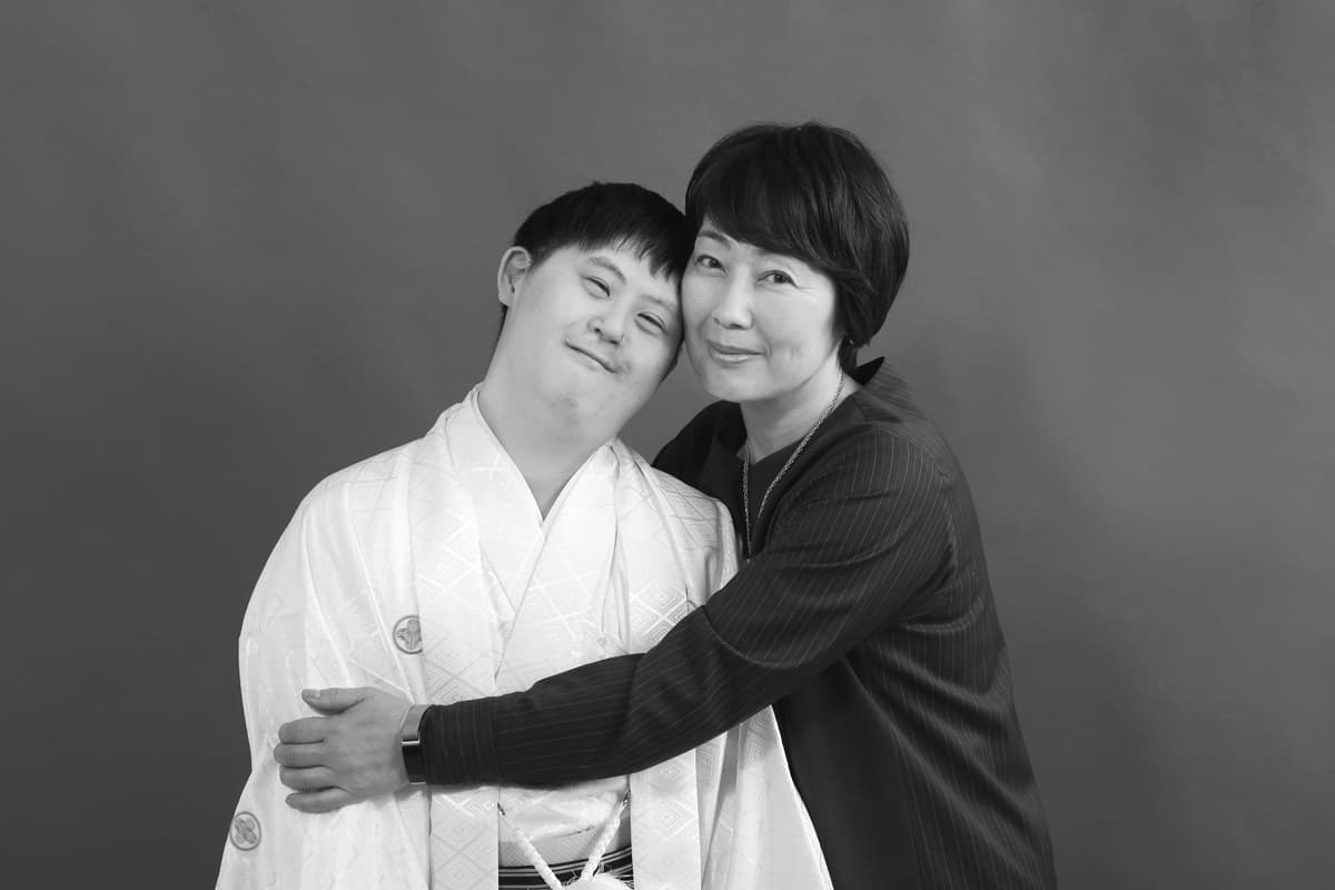 袴姿のダウン症男子と抱き合う母親